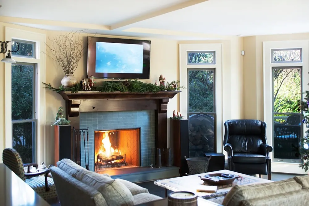 Living room with a stone fireplace adjoining a remodeled kitchen